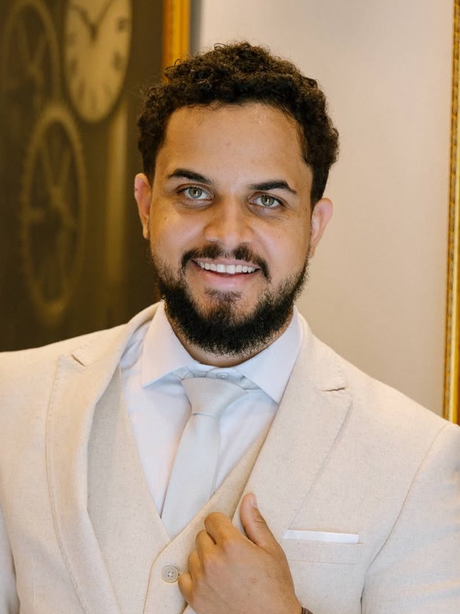Retrato de Matheus Pedro do Carmo sorrindo, de terno bege